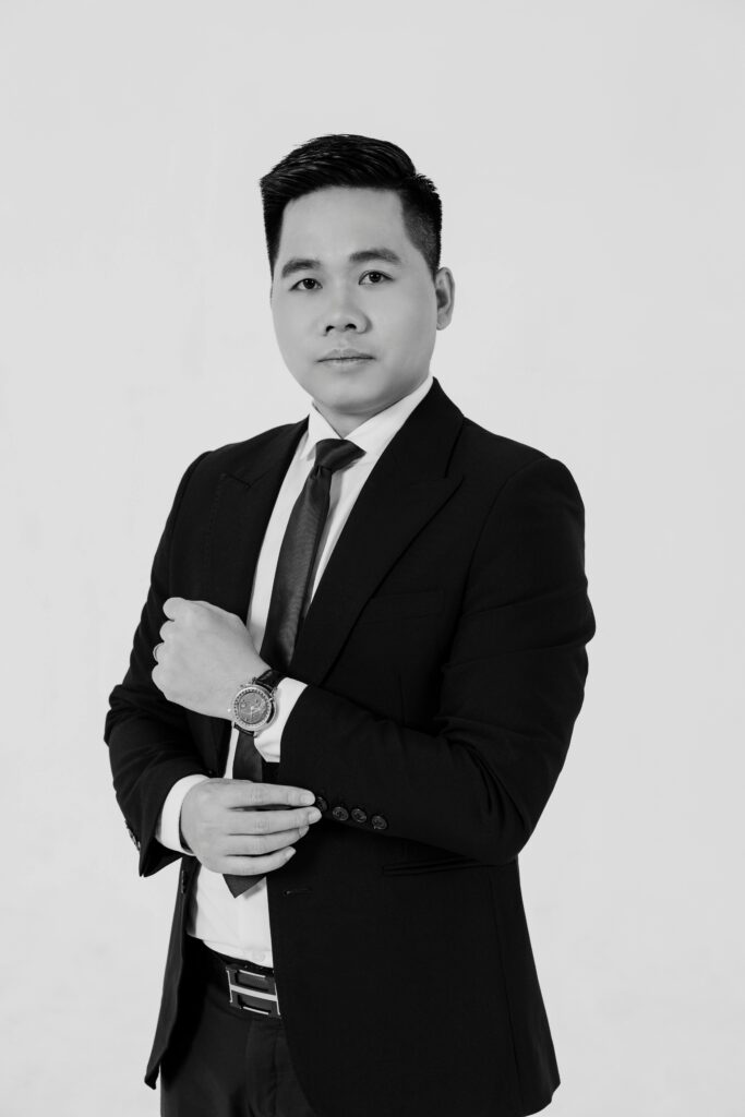 testimonial Confident Asian man in a suit posing in a studio setting, black and white photo.